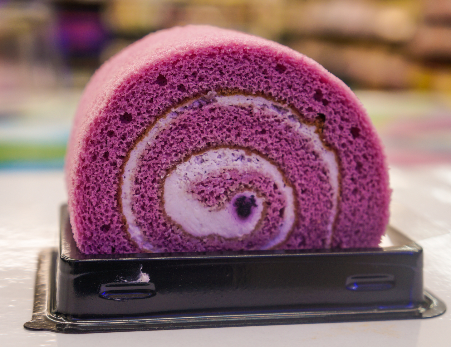 A photo of an Okinawan sweet potato cake roll. The cake roll has a rich purple color and is made with Okinawan sweet potatoes, creating a vibrant and visually appealing dessert. The alt text provides a visual description of the Okinawan sweet potato cake roll, emphasizing its unique purple hue and the use of Okinawan sweet potatoes as a key ingredient.